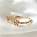 Eleganter goldener verstellbarer Blumenring mit rosa Zirkonia auf weißem Seidenhintergrund. - Einstellbar Offen / Rosa Zirkonia Welliger Blumenstil (JZ088)