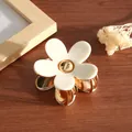Detailed close-up of a small white acetate flower hair claw clip with elegant gold finish - Milky White