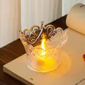Close-up of crown-shaped transparent LED tea light with a warm yellow glow - Clear