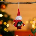 High-quality close-up of a festive plush snowman ornament hanging from a rustic branch - Red Hat Green Body Snowman