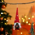 Close-up of a festive Christmas gnome ornament hanging from a tree branch with warm lights. - Braid Style Red Hat Green Body