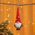 Nahaufnahme eines festlichen roten gestrickten Weihnachtsgnom-Ornaments an einem Ast - Bart-Stil / Roter Hut Grüner Körper
