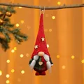 Nahaufnahme eines handgefertigten roten gestrickten Weihnachtswichtel-Anhängers am Ast - Geflochtener Stil / Roter Hut Grüner Körper