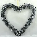 Shiny silver heart-shaped tinsel Christmas wreath hanging on a soft white background. - 30x35cm / Silver