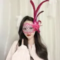 Detailansicht einer rosa Spitzen-Maskerade-Maske mit Federn und Blume an einer Frau - Feder Blume Spitze Stil / Fuchsia