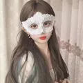 Detailed view of a white lace masquerade mask with rhinestone detailing worn by a model. - White