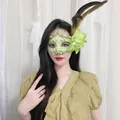 Nahaufnahme einer eleganten grünen Spitzenmaske mit Blumen- und Federakzenten - Feder Blume Spitze Stil / Grün