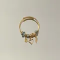 Close-up detail of an adjustable stainless steel charm bracelet with golden heart charm - Angel Wings Heart Pendant Style / Green
