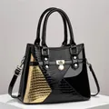Detail of black and gold patent leather handbag with lizard texture and gold hardware - Black