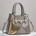 Detailed view of grey patent leather handbag with gold lizard texture pattern - Gray