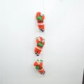 Detail view of three plush Santa Claus figures climbing a white rope ladder decoration - Triple Santa Claus Ornament / 25cm