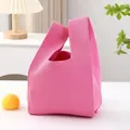 Detailed view of a stylish pink knitted wrist bag with minimalist design on table - 20x38cm / Solid Rose Red