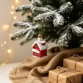 Red and white house Christmas tree ornament on snow-covered pine branch with warm lights - Christmas House Pendant