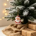 Roter und weißer Weihnachtsmann-Christbaumschmuck an einem schneebedeckten Kiefernzweig - Weihnachtsmann Anhänger