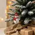Weihnachtsschneemann-Anhänger mit rotem Hut am Weihnachtsbaum in festlicher Kulisse - Weihnachts-Schneemann-Anhänger