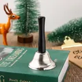 Close-up of a silver Christmas handbell with a black wooden handle on a green book - Silver