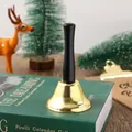 Macro view of a classic gold Christmas handbell with a black handle on a decorative book - Gold