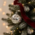 Elegante silberne Weihnachtskugel mit Glitzerhaus-Design am verschneiten Baum - Silberne Kugel mit Hausmuster Anhänger