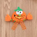 Detailed shot of a plush Halloween pumpkin brooch with polka dot bow and green hat. - Glowing Smiling Pumpkin