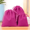Set aus drei magentafarbenen Samtbeuteln mit Kordelzug für Schmuck auf einem Holztisch - Fuchsia