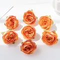 Close-up of seven vintage orange silk rose heads for DIY crafts and wedding decor. - Orange