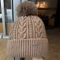 Warm brown cable-knit winter beanie with a fluffy faux fur pom-pom and metal accent - One Size / Coffee