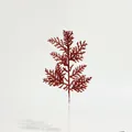 Detail view of a glittery red artificial Christmas pine branch on white background - Red Pine Needle
