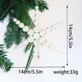 Close-up of a white pearl snowflake Christmas ornament hanging on a pine branch - Snowflake with Pearl Style