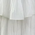 Macro detail shot showing the white pleated fabric layers and fine texture of a summer dress - White