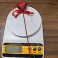 Close-up of a red glitter heart floral pick with bow showing 2g weight on a digital scale - 1 Piece / Red