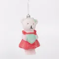 Close-up detail of a white glitter bear Christmas ornament in a red dress - Glitter Cat