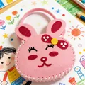 Primer plano de un bolso de conejo de fieltro rosa hecho a mano para niños con detalles DIY - Estilo Conejo