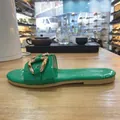 Zijaanzicht van een groene platte sandaal met een goudkleurige metalen kettinggesp. - Groen