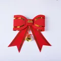 Close-up detail of a red and gold Christmas bow with a gold bell and lettering - 26.5x30.5cm / Red