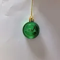 Macro detail of metallic green St. Patrick's Day coin ornament with embossed hat design - Green (Single)