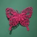 Close-up shot of a vibrant pink glittery butterfly decoration with intricate hollow design. - 12cm / Plum Red