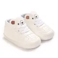 Vue détaillée de baskets blanches pour bébé avec un motif d'ours mignon sur la languette. - Blanc