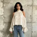 Detalle de blusa de satén con hombros descubiertos y mangas acampanate en modelo de pared. - S / Tops / Albaricoque