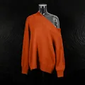 Detail of a bright orange off-shoulder knit sweater featuring a relaxed French style fit. - One Size / Tops / Orange