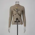 Close-up of khaki ribbed knit top featuring front twist cutout and gold eye brooch - S / Tops / Khaki