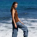 Modella indossa un top marrone senza maniche stile francese su uno sfondo oceanico. - Taglia S / Top / Marrone