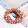 Close-up of an elegant rose gold pearl beaded hair tie on a magazine background. - Coffee