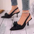 Detail shot of elegant black pointed-toe slingback heels with a large silk bow - 35 / Black