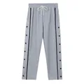 Detail van grijze tear-away broek met zwarte zijstrepen en functionele drukknoppen. - Lichtgrijs