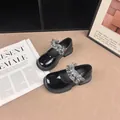 Detail of black patent leather Mary Jane shoes with grey ruffled pearl straps on a magazine. - Size 27 (Inner Length 17cm) / Black
