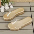 Detail view of gold platform slide sandals featuring a clear PVC strap on wooden floor - 36 / Clear