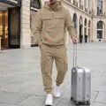 Fashionable man wearing a khaki hooded cargo tracksuit with suitcase on a city street - Khaki