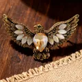 Detailed macro view of vintage gold eagle brooch featuring a heart crystal and cat eye stones - Antique Gold Champagne Eagle Brooch