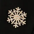 Vue détaillée d'une broche flocon de neige dorée festive ornée de strass étincelants de qualité. - Broche Flocon de Neige (7592)