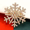 Close-up of gold-tone Christmas snowflake brooch encrusted with clear rhinestones. - Gold
